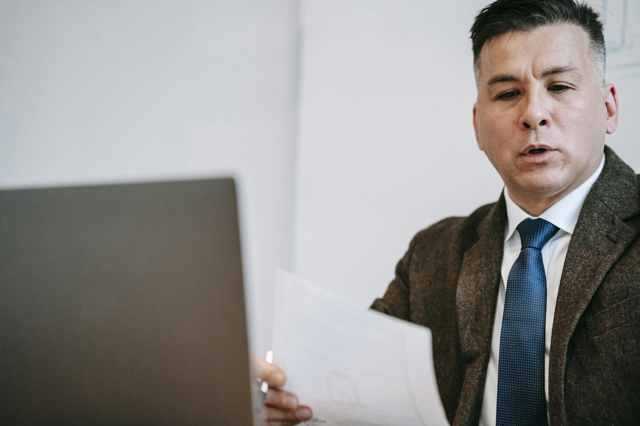 A focused lecturer in a suit, using a laptop for an online session.