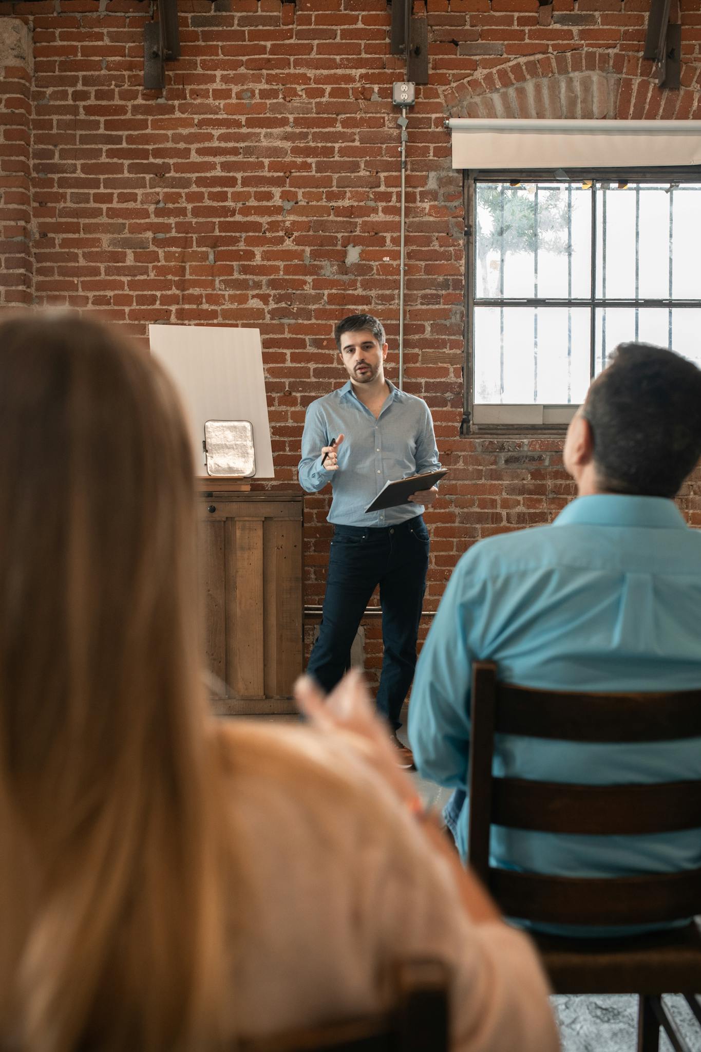 Man teaching an adult education class with brick wall backdrop.